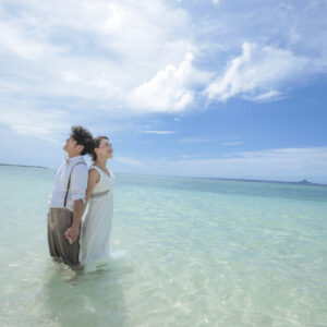 ドレスを着た新婦と新郎が海の中に入って撮影されたウェディングフォト