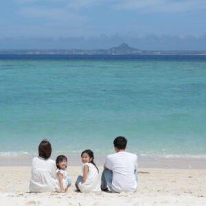 父親と母親、息子、娘の4人の沖縄の浜辺での家族写真